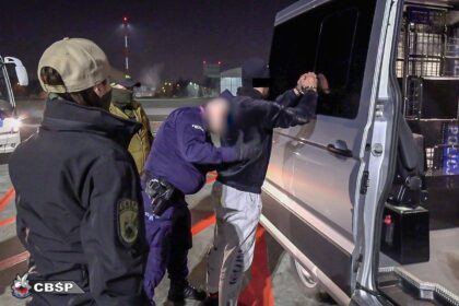 Policjanci prowadzący zatrzymanego szefa grupy przestępczej znanej jako gang Smoka.