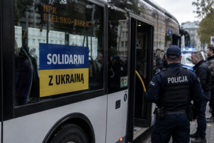 Policjant na tle autobusu z banerem wspierającym Ukrainę